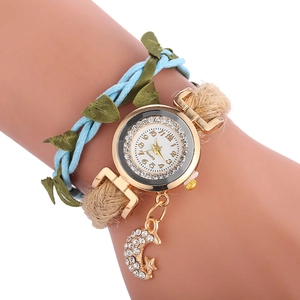Détail d'une montre bohème dorée avec lunette diamantée, pendentif lune et lien tressé