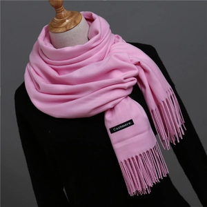 Close-up of pink cashmere-like scarf texture with fringe details and woven material label