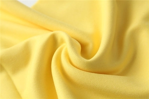 Macro shot of bright yellow cashmere-like knit fabric showing soft texture and tassel detail