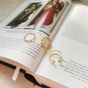 Detailed close-up of a three-piece gold geometric ring set styled on an art book