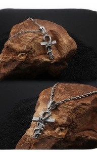 Close-up of gothic stainless steel snake wrapped ankh cross pendant on stone