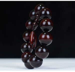 Macro detail of dark red sandalwood beads showing natural grain and high-density oil finish