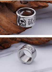 Close-up of punk pirate skull engraving and English motto on wide titanium steel ring