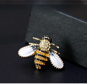 Macro shot of bee brooch with black and orange rhinestones on golden alloy base