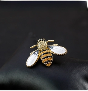 Macro shot of bee brooch with yellow rhinestones and enamel wings on black jewelry pillow