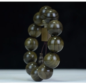 Macro detail of aged Phoebe zhennan beads with fine golden threads and gourd charm