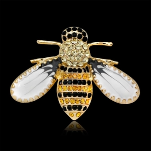 Gold bee brooch with yellow and black rhinestones on a black background with reflection