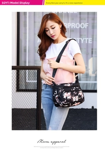 Detail of floral print nylon shoulder bag featuring multiple zippered compartments and strap