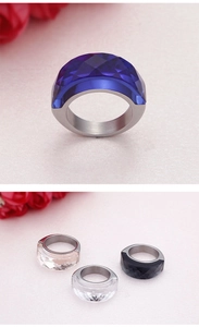 Detail of wide stainless steel rings featuring multi-faceted crystals in blue and clear