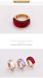 Dettaglio dell'anello in acciaio inossidabile dorato con pietra di cristallo rosso