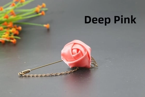 Close-up of deep pink satin rose brooch with golden leaf charms and hanging chains