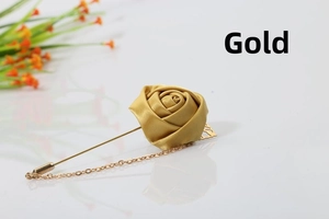 Detail of a golden satin rose brooch with delicate metal chain for suit lapels