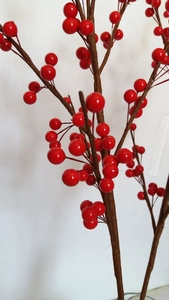 Close-up of bright red artificial holly berries and brown textured stems for New Year decor