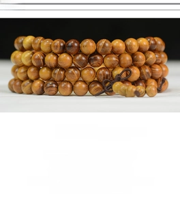 Macro des perles en bois de Bocote avec grain naturel et tons dorés sur le bracelet