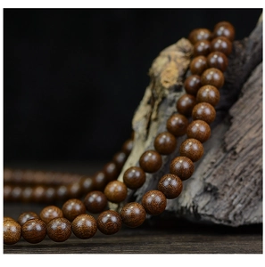 Macro shot of 108 sandalwood prayer beads showing dark brown wood grain texture