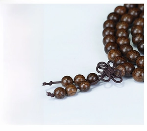 Macro shot of dark sandalwood beads with natural grain and brown woven tassel