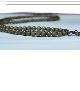Macro detail of dark green Phoebe zhennan wood beads with natural texture and woven knot