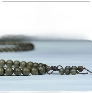 Macro shot of 108 polished ebony wood prayer beads with natural grain and Chinese knot detail
