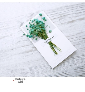 Macro detail of teal dried gypsophila on handmade white greeting card with poetic text