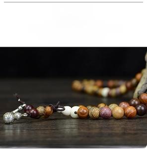 Macro shot of colorful mixed wood prayer beads with polished silver metal pendant