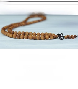 Detailed view of Indonesian sandalwood beads with a brown decorative Chinese knot