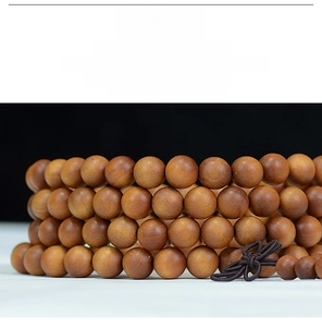 Macro view of 108 sandalwood prayer beads with natural wood grain and woven knot