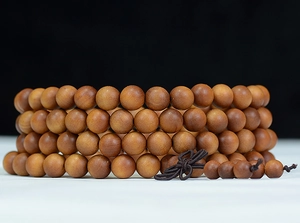 Macro detail of natural sandalwood beads showing fine wood grain and dark brown silk knot