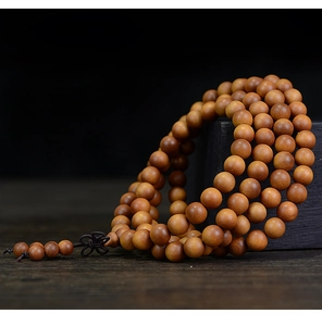 Macro shot of 108 sandalwood prayer beads with polished texture on a dark wooden base