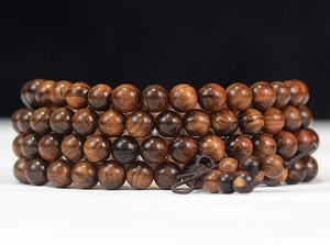 Macro detail of natural dark rosewood prayer beads with a traditional knot tassel