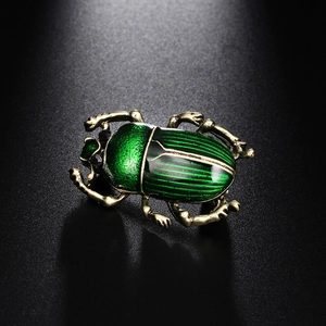 Gros plan d'une broche scarabée vintage avec émail vert brillant et détails dorés