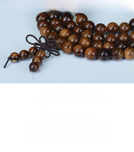 Macro detail of dark Dalbergia wood beads showing distinct grain and a Chinese knot