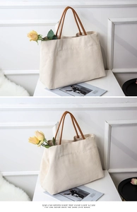 Detail of minimalist canvas tote bag with brown leather handles on a decorative background