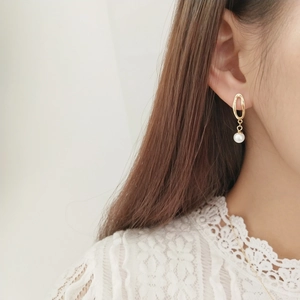 Detail of elegant gold irregular hollow earring with white pearl on model ear