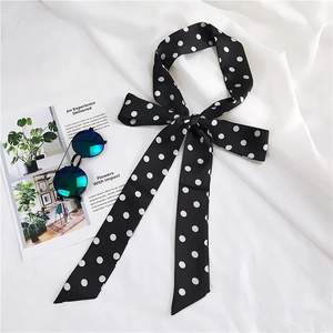 Close-up of a long black polka dot skinny scarf tied in an elegant bow with sunglasses