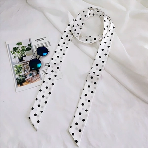 Close-up of elegant black and white polka dot skinny silk scarf styled on high-end fashion magazine