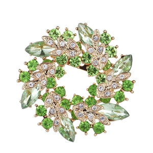 Macro shot of gold floral brooch with green gemstones and sparkling rhinestones