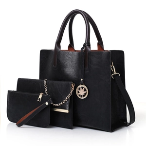 Three-piece set of black faux leather tote bags with gold leaf pendant detail