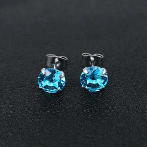 Macro shot of bright blue round zircon studs with silver stainless steel four-prong setting