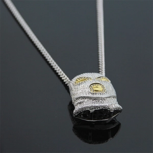 Macro shot of silver hip hop balaclava mask pendant with clear stones and gold details