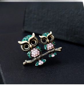 Detailed macro of vintage owl brooch with emerald green and pink crystal rhinestones