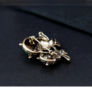 Detail of vintage owl brooch back with copper pin and green crystal accents on edges