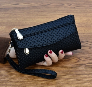 Detail of classic black quilted wristlet clutch with golden zipper and leather texture
