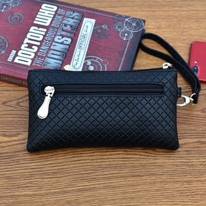 Minimalist black quilted wristlet wallet with double zippers on a wooden desktop