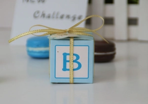 Close-up of blue square party gift box with golden ribbon and letter B decoration