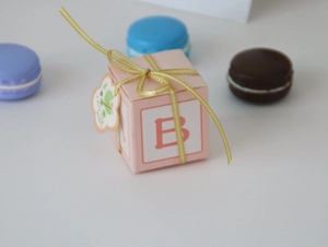 Detailed view of pink paper candy box with yellow ribbon and letter B for parties
