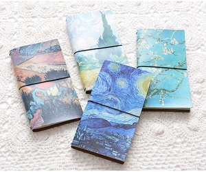 Detail of Van Gogh art notebooks with elastic bands on a white lace background