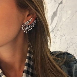 Detail of silver asymmetric crystal wing ear cuff shown on a model against marble