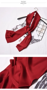Detailed macro view of deep red satin silk scarf showing fine fabric texture and high luster