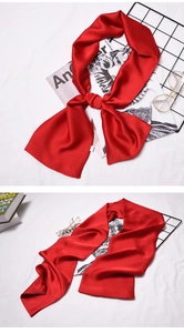 Close-up of a premium red silk neck scarf styled in a knot on a minimalist background