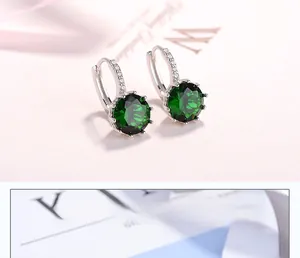 Macro shot of silver hoop earrings with large round green zircon in six-prong setting